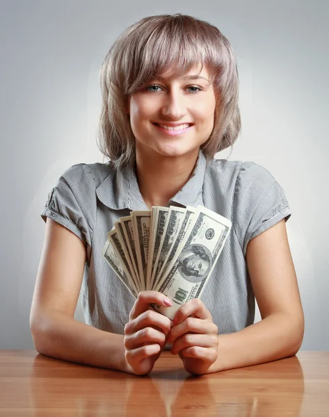 Woman sitting on the desk and holding dollars — Stock Photo, Image
