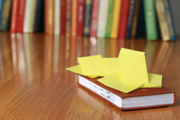 Bok med klistremerke på skrivebordet mot bøker – stockfoto
