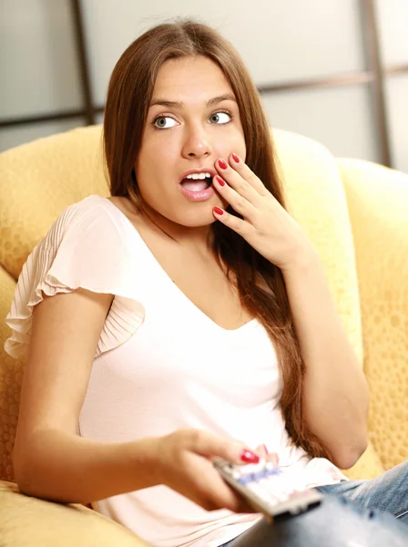 Woman sitting on sofa with remote control panel TV — Stock Photo, Image