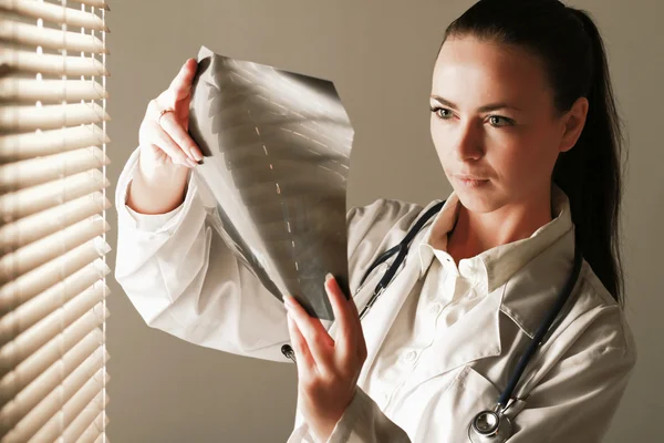 Young woman doctor is standing near window — Stock Photo, Image
