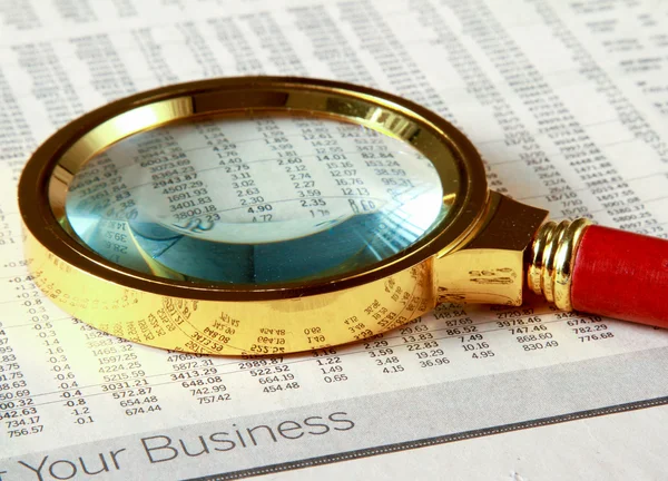 Looking through magnifying glass to financial report — Stock Photo, Image