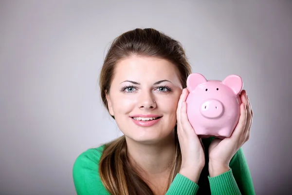 Young woman showing her pink piggy bank — Stock Photo, Image