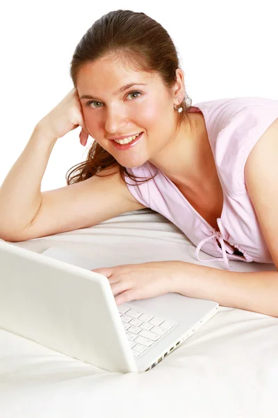 Молодая женщина лежит на кровати с ноутбуком — стоковое фото