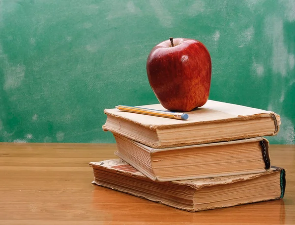 Una manzana roja en un montón de libros — Foto de Stock