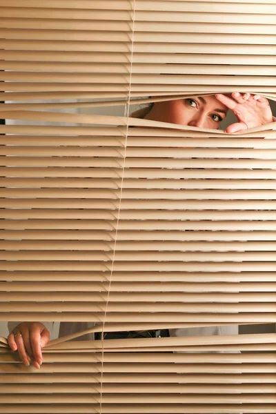 Retrato de uma mulher olhando através das cortinas . — Fotografia de Stock