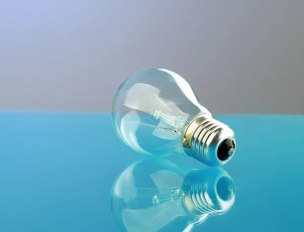 Light bulb isolated on blue glossy background. — Stock Photo, Image