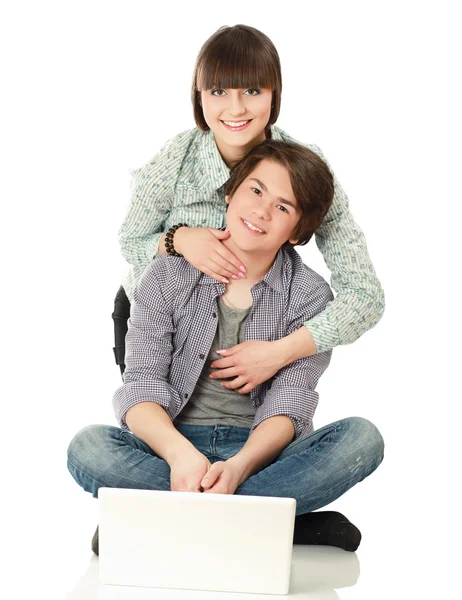 Um casal sentado no chão atrás de um laptop — Fotografia de Stock