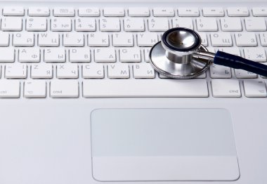 Beyaz dizüstü bilgisayar üzerinde bir stetoskop.