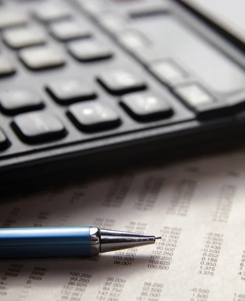 Pen en rekenmachine op papieren tafelnummers. — Stockfoto