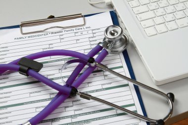 Medical record amd a stethoscope near a laptop clipart