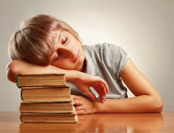 Молодая женщина спит на стопке книг — стоковое фото