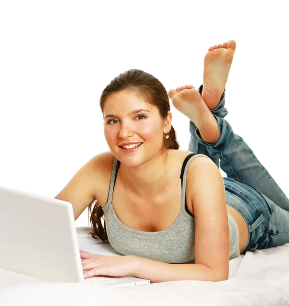 Mujer joven feliz con el ordenador portátil acostado en la cama — Foto de Stock