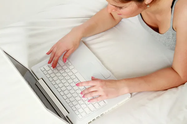 Glad ung kvinna med laptop liggande på sängen — Stockfoto