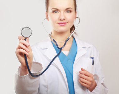 Steteskoplu bir kadın doktor dinliyor.