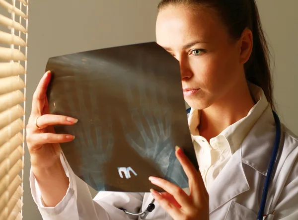 La mujer está de pie cerca de la ventana y examinando rayos X — Foto de Stock