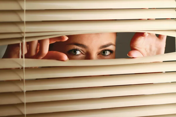 Жінка дивиться через штори — стокове фото