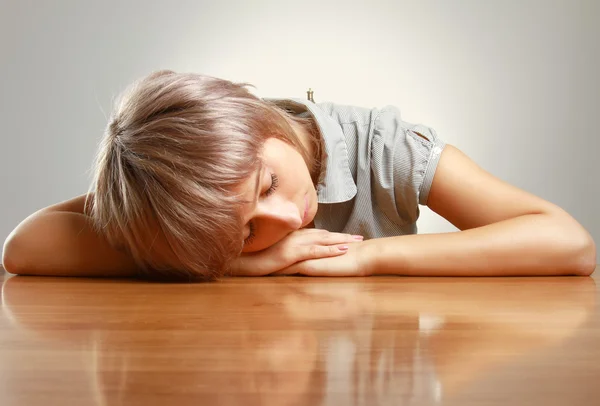 Eine müde Frau schläft auf dem Tisch — Stockfoto