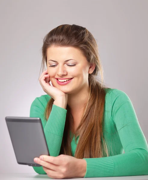 Mujer sentada en el escritorio y sosteniendo la computadora de mesa plana — Foto de Stock