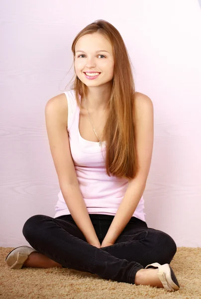 A young girl sitting on the floor near to the wall — Stock Photo, Image