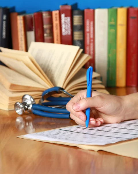 Primer plano de las manos del médico de la escritura en un escritorio de madera — Foto de Stock