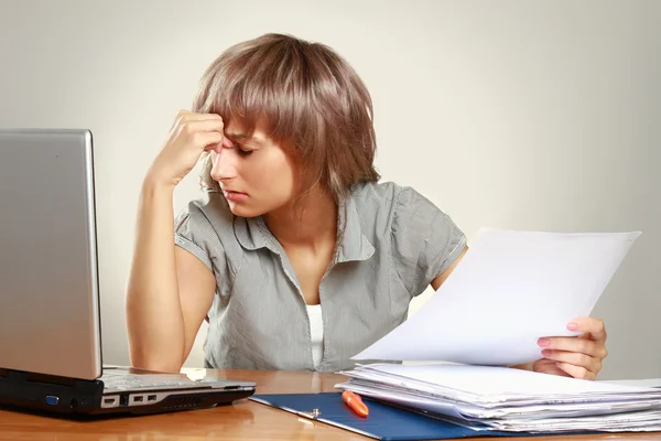 A tired young woman sitting at the desk — Stock Photo, Image