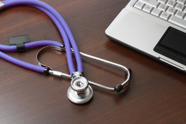Ein violettes Stethoskop auf einem weißen Laptop — Stockfoto