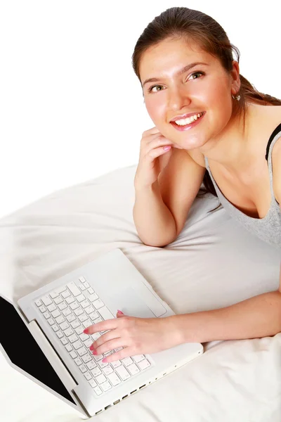 Young smiling with laptop lying on bed isolated — Stock Photo, Image