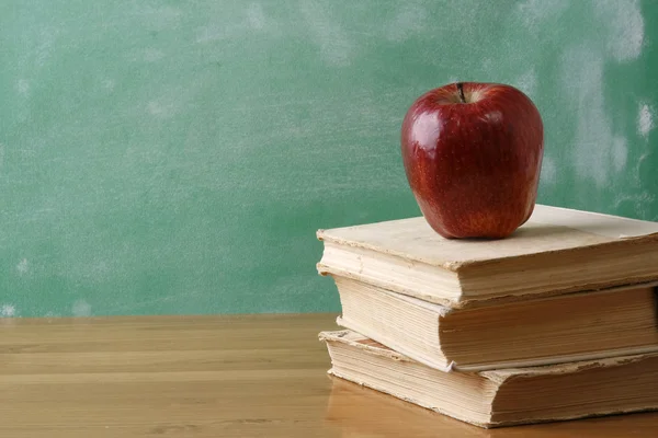 A chalkboard with an apple and a pile of books — Stock Photo, Image