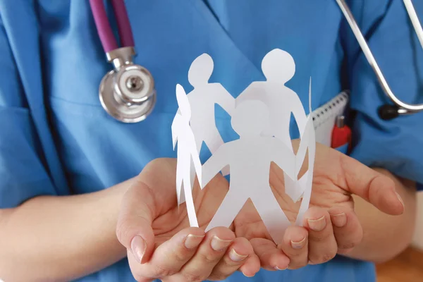 A female doctor holding paper people — Stock Photo, Image