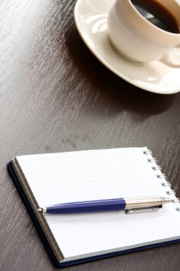 fincan kahve ve bir defter kalem üzerinde ahşap bir masa ile