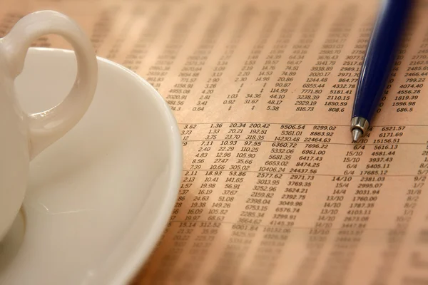 Primo piano di una tazza di caffè e una penna su un giornale del mattino — Foto Stock