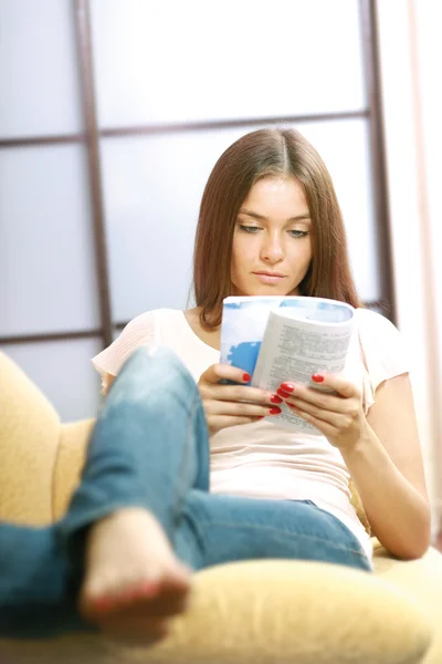 Woman on the couch with a book — Stock Photo, Image