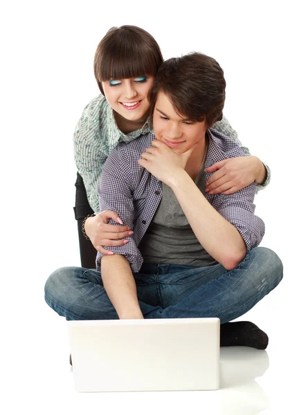 Casal sentado no chão atrás de um laptop — Fotografia de Stock