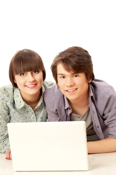 Paar op de vloer liggen achter een laptop — Stockfoto