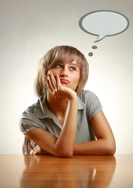 A pensive young woman sitting at the desk — Stock Photo, Image