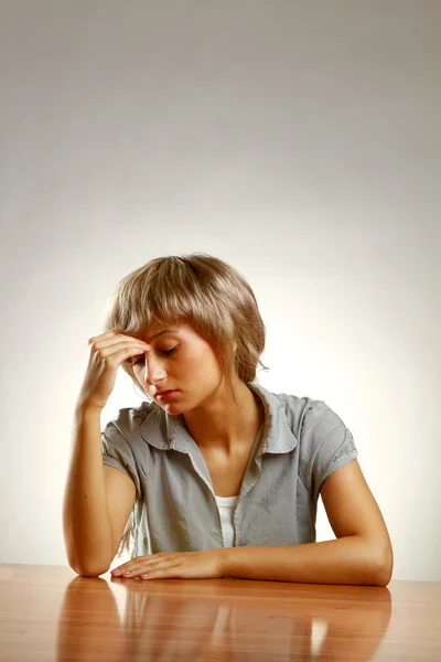 En ung trött kvinna sitter vid skrivbordet — Stockfoto