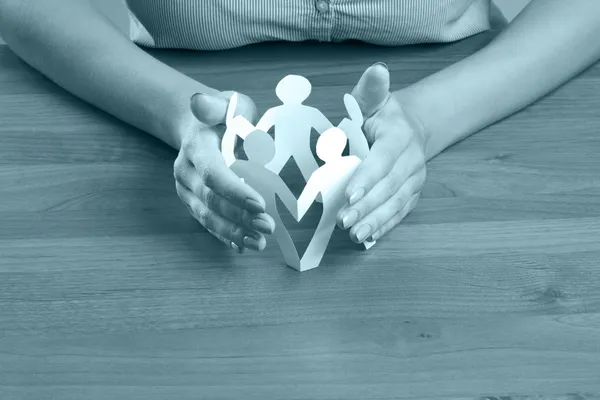 Female hands taking care of paper people — Stock Photo, Image