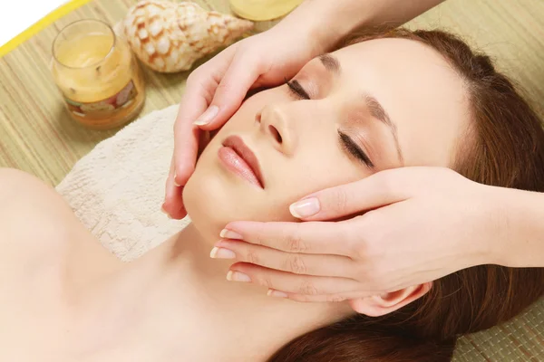 Handen masseren een mooie jonge vrouw gezicht — Stockfoto