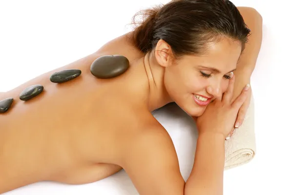 Lächelnde Frau erhält eine Therapie mit heißen Steinen im Wellnesszentrum — Stockfoto