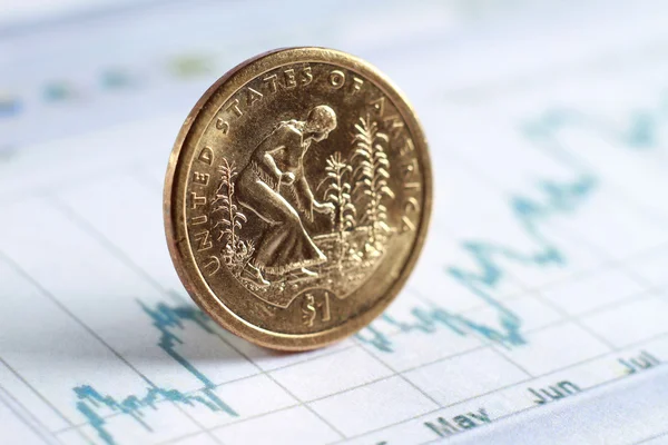 A golden coin on diagram papers — Stock Photo, Image