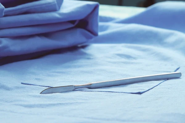 Scalpel liggend op medische uniform — Stockfoto