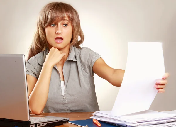 Eine müde junge Frau sitzt am Schreibtisch — Stockfoto