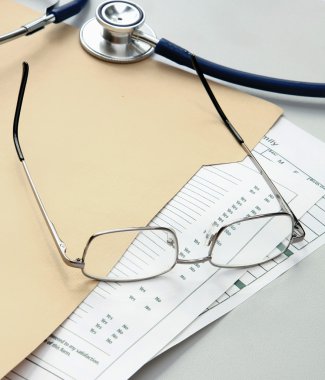 kalem, stetoskop, kağıtları ve gözlük ile klasör.