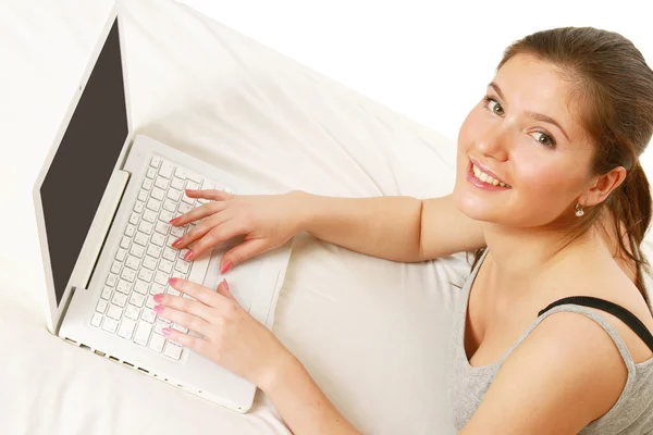 A woman works with a laptop lying — Stock Photo, Image