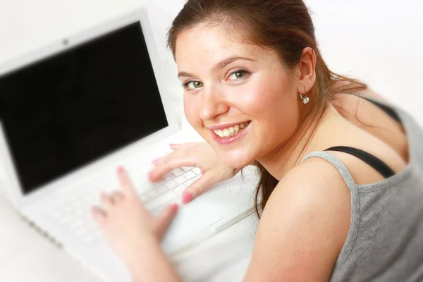 Uma mulher sorrindo trabalhando com um laptop — Fotografia de Stock