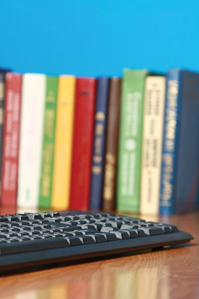 Teclado acostado en un escritorio con libros — Foto de Stock