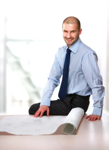 Um belo homem de negócios sentado em uma mesa com rascunhos — Fotografia de Stock