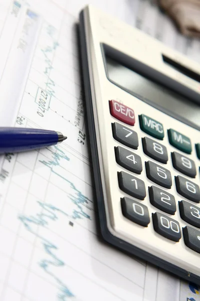 A calculator and a pen over papers — Stock Photo, Image