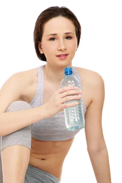 Sprawny, młoda dziewczyna, siedząc na podłodze z butelką wody — Zdjęcie stockowe