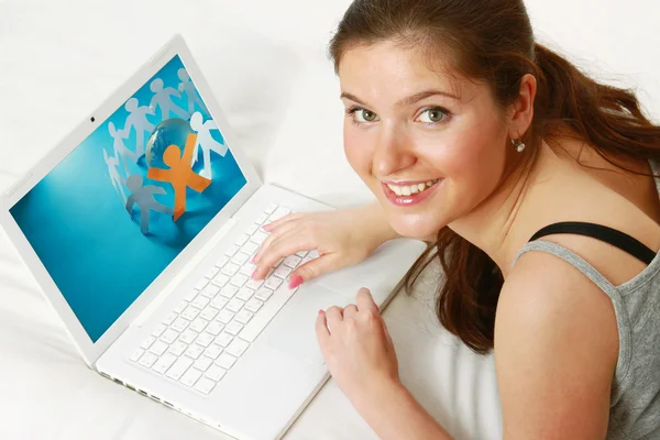 Genç kız kanepe üzerinde bir dizüstü bilgisayar kullanarak — Stok fotoğraf